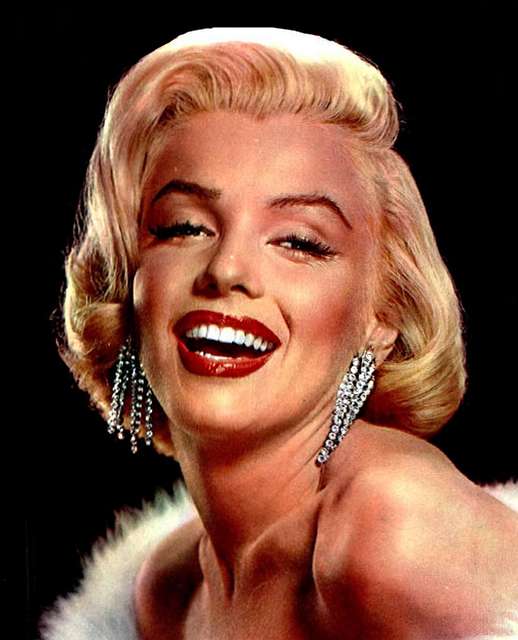 Original Caption: Marilyn Monroe, her photogenic trademark: the lingering look, the moist open lips, the silky hair and the beauty mark, they're all caught in this portrait.